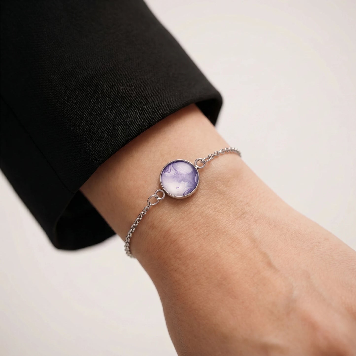 Model wearing Dar Suad stainless steel bracelet featuring marbling artwork in purple and white.