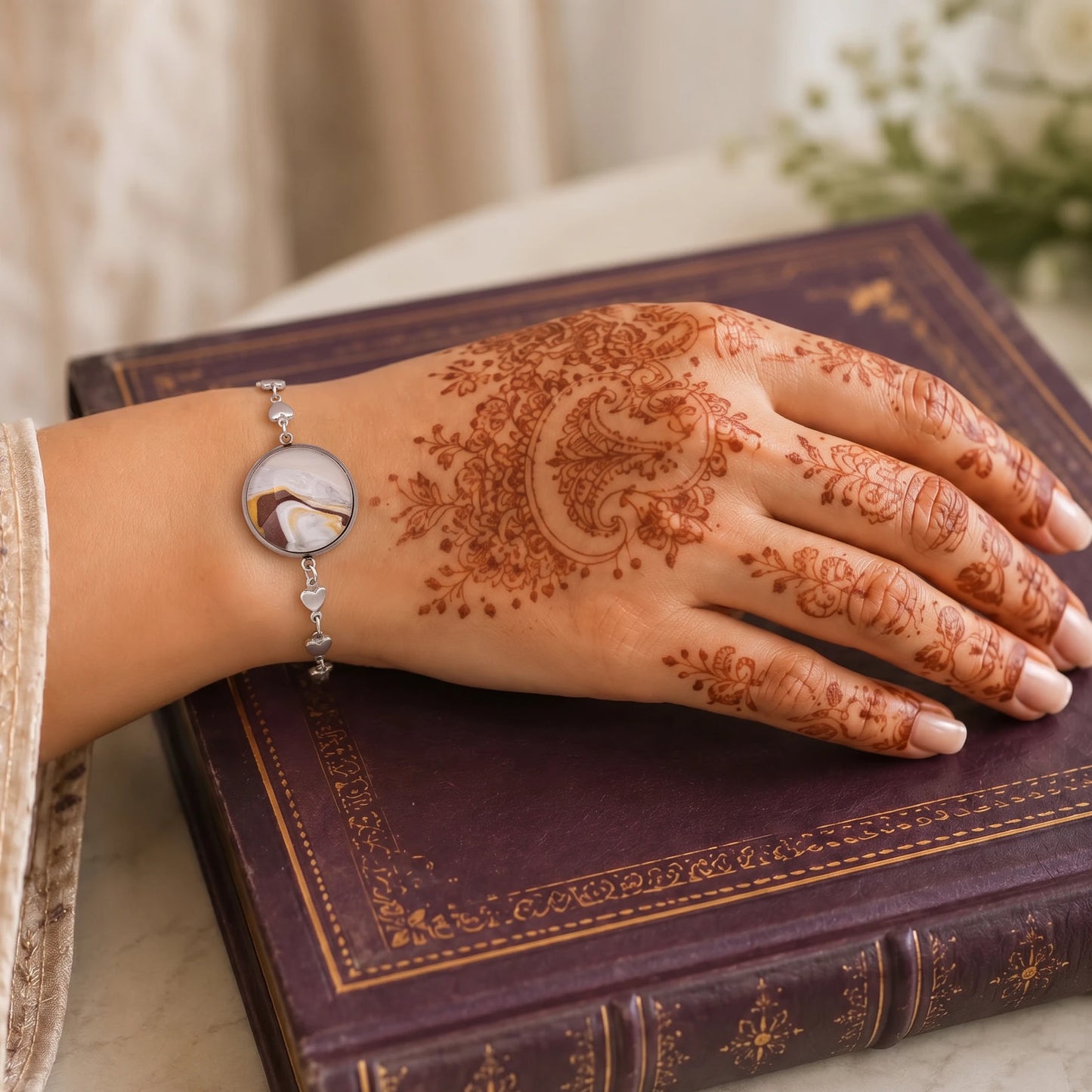Model wearing Dar Suad stainless steel bracelet featuring marbling artwork in brown, yellow and white.