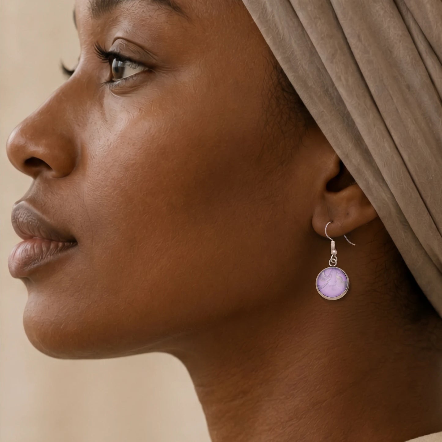 Model wearing Dar Suad stainless steel earrings featuring marbling artwork in purple and silver.