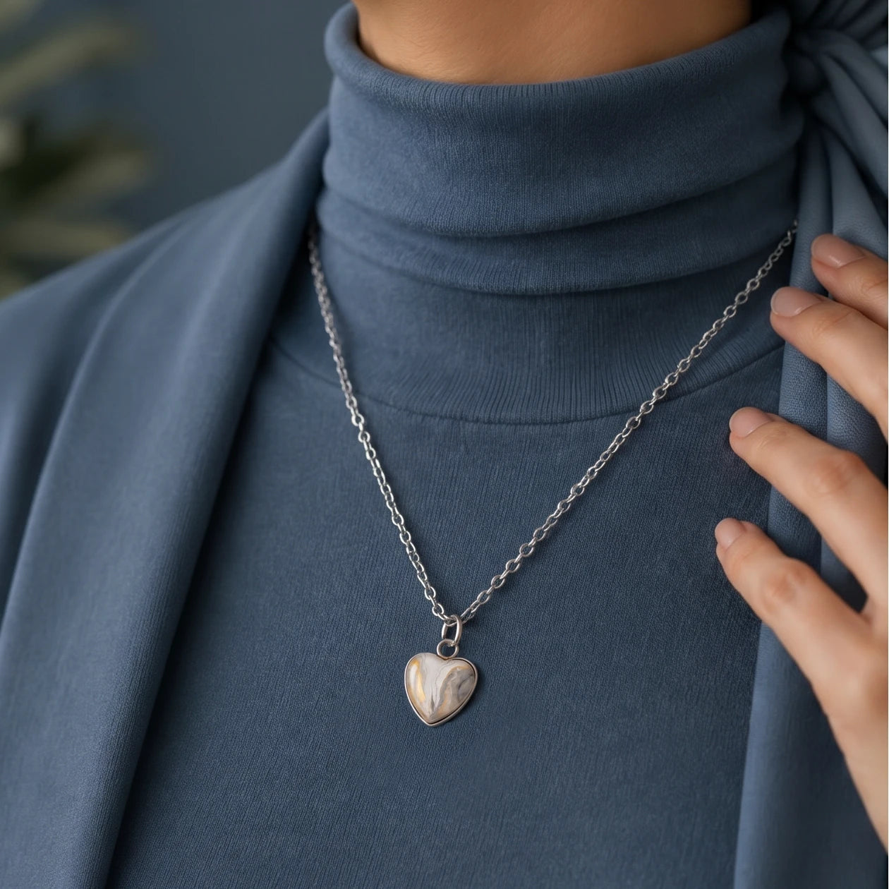 Model wearing Dar Suad stainless steel necklace featuring marbling artwork in white, yellow and grey.