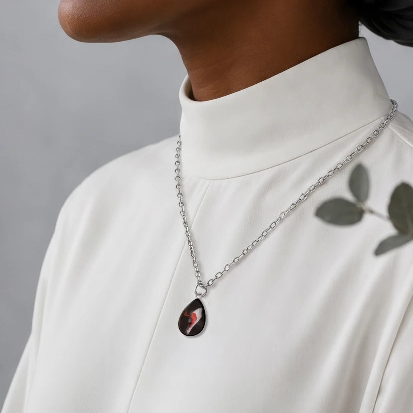 Model wearing Dar Suad stainless steel necklace featuring abstract artwork in black, red, and silver.