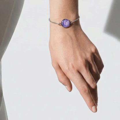 Model wearing Dar Suad stainless steel bracelet featuring marbling artwork in purple and white.