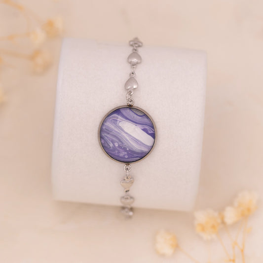 Dar Suad bracelet featuring marbling artwork in purple, white, and silver with a stainless steel setting.