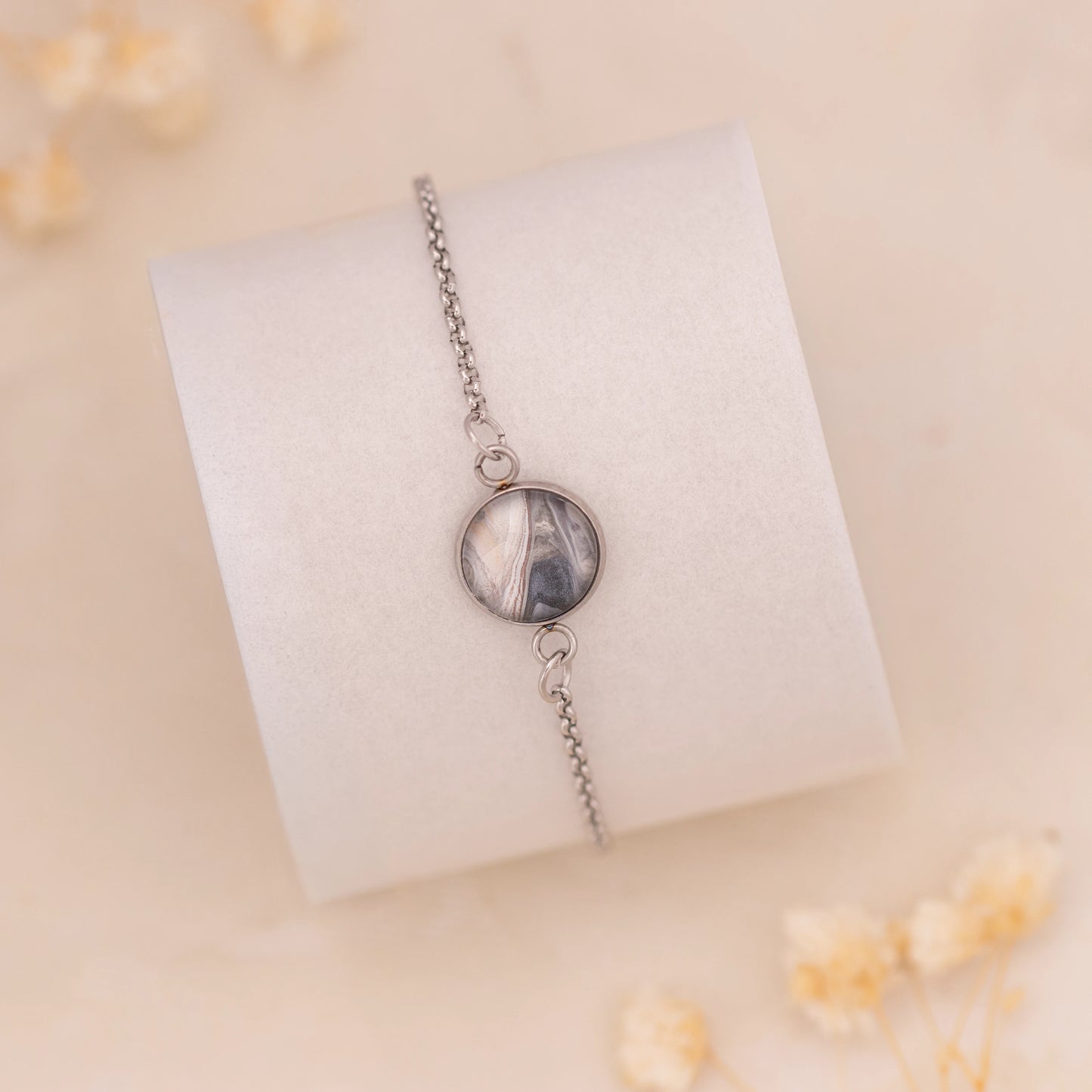 Dar Suad bracelet featuring marbling artwork in grey, silver, and beige with a stainless steel setting.