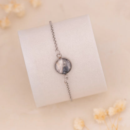 Dar Suad bracelet featuring marbling artwork in grey, silver, and beige with a stainless steel setting.