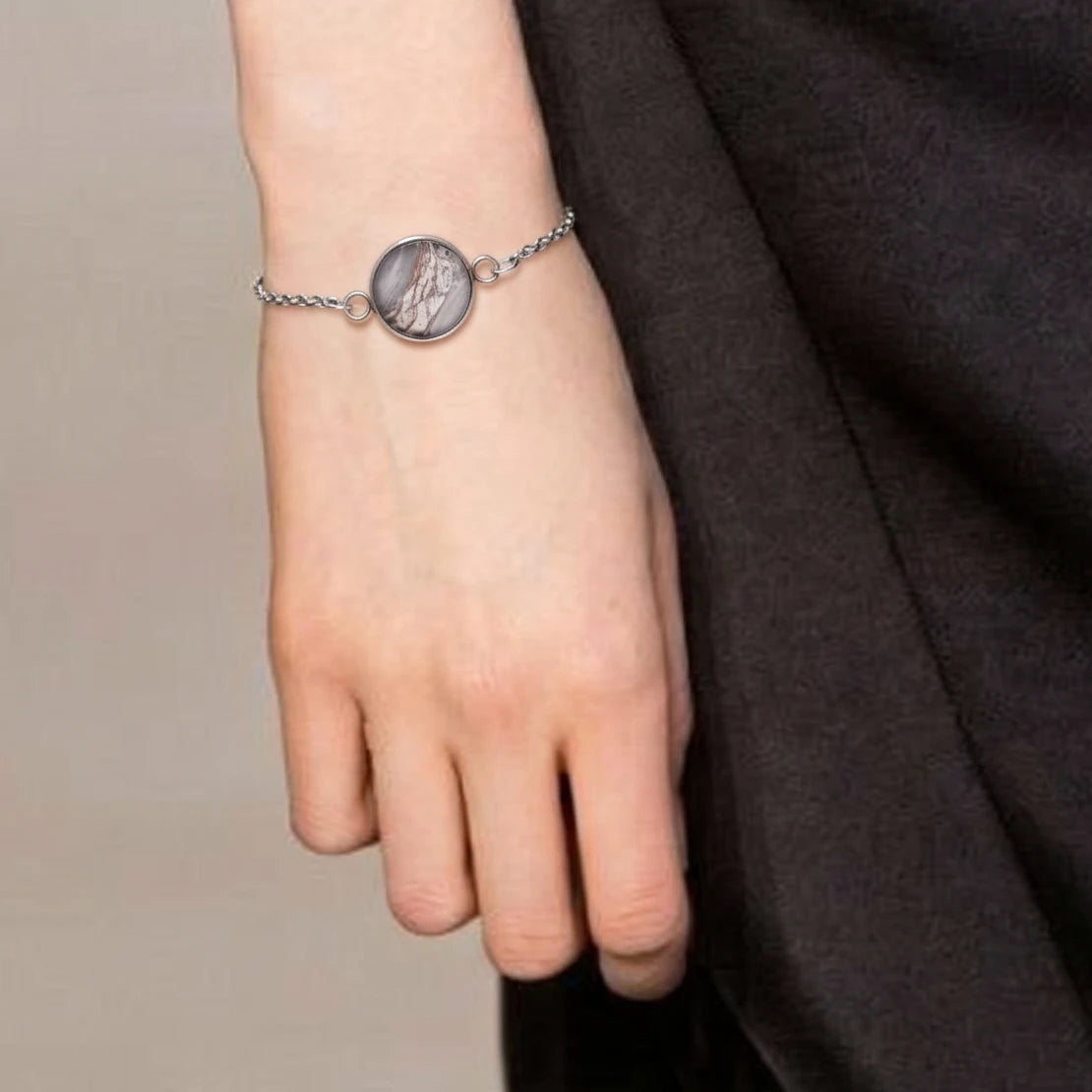 Model wearing Dar Suad stainless steel bracelet featuring marbling artwork in grey, brown, and white.
