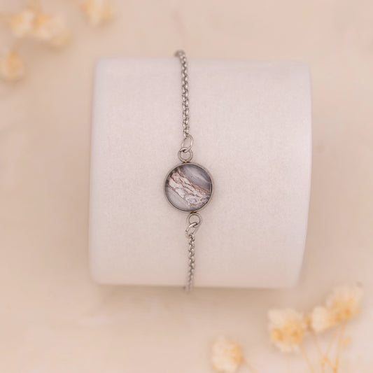 Dar Suad bracelet featuring marbling artwork in grey, brown, and white with a stainless steel setting.