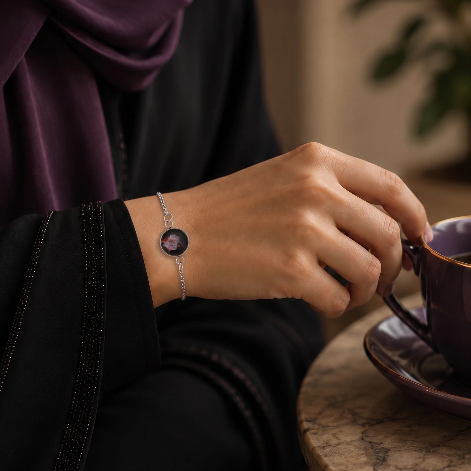 Model wearing Dar Suad stainless steel bracelet featuring abstract artwork in black, silver, and red.