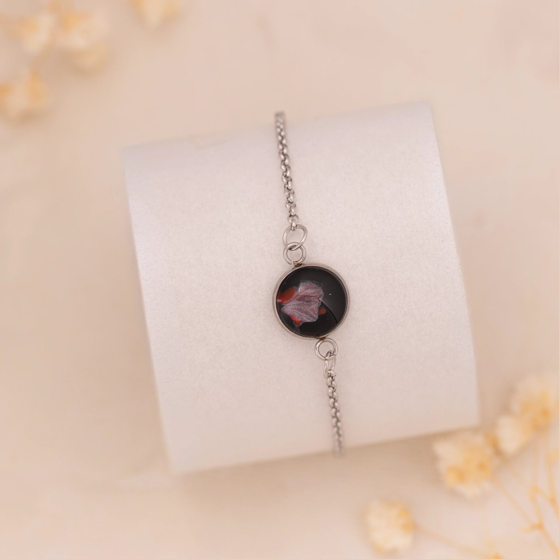 Dar Suad bracelet featuring abstract artwork in black, red, and silver with a stainless steel setting.