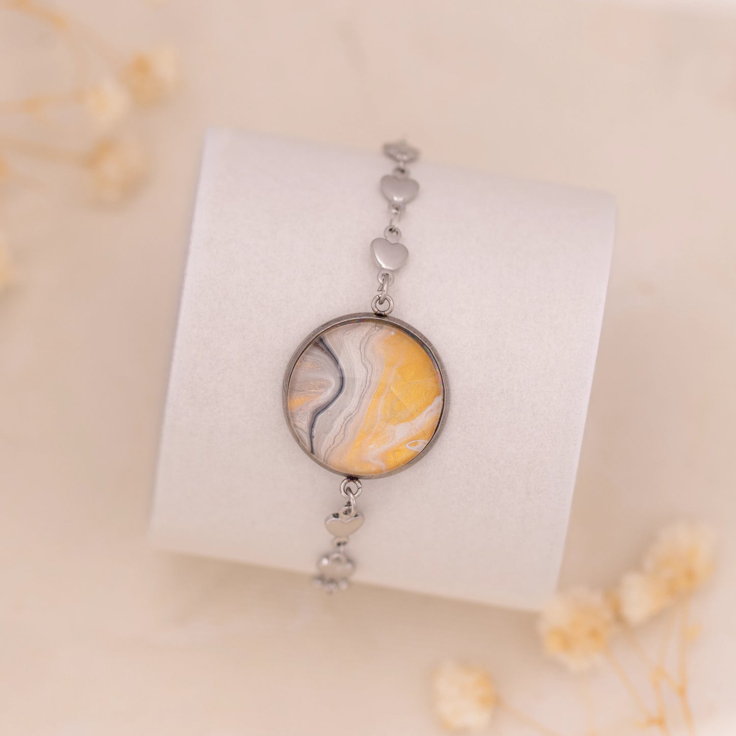 Dar Suad bracelet featuring marbling artwork in yellow, white, and grey with a stainless steel setting.