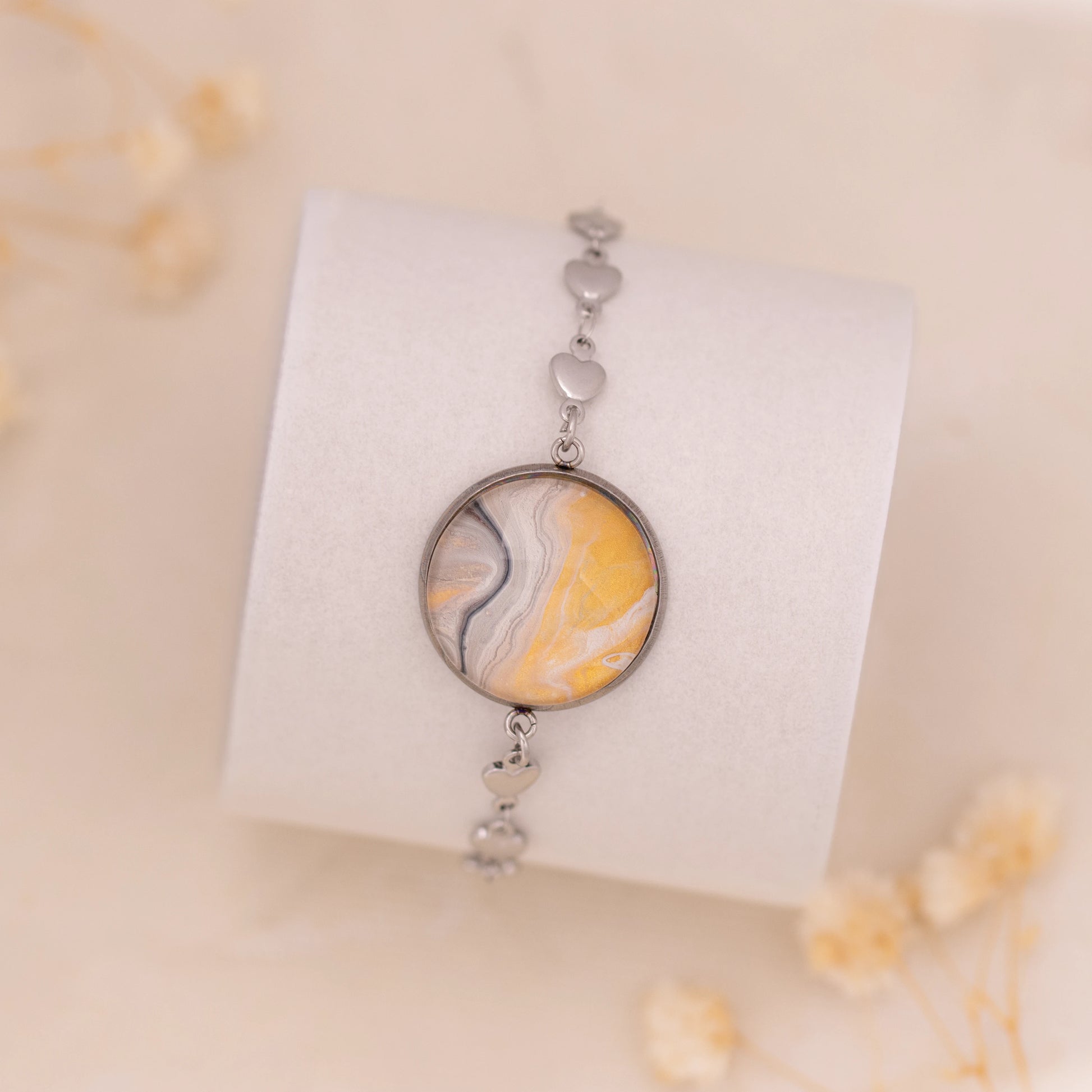 Dar Suad bracelet featuring marbling artwork in yellow, white, and grey with a stainless steel setting.