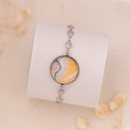 Dar Suad bracelet featuring marbling artwork in yellow, white, and grey with a stainless steel setting.