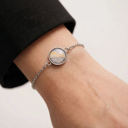 Model wearing Dar Suad stainless steel bracelet featuring marbling artwork in grey, yellow, and white.