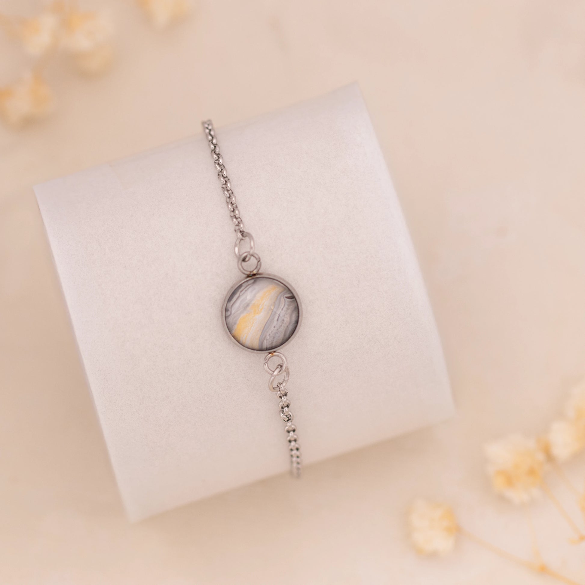 Dar Suad bracelet featuring marbling artwork in grey, yellow, and white with a stainless steel setting.