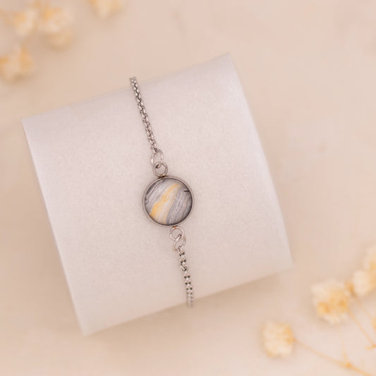 Dar Suad bracelet featuring marbling artwork in grey, yellow, and white with a stainless steel setting.
