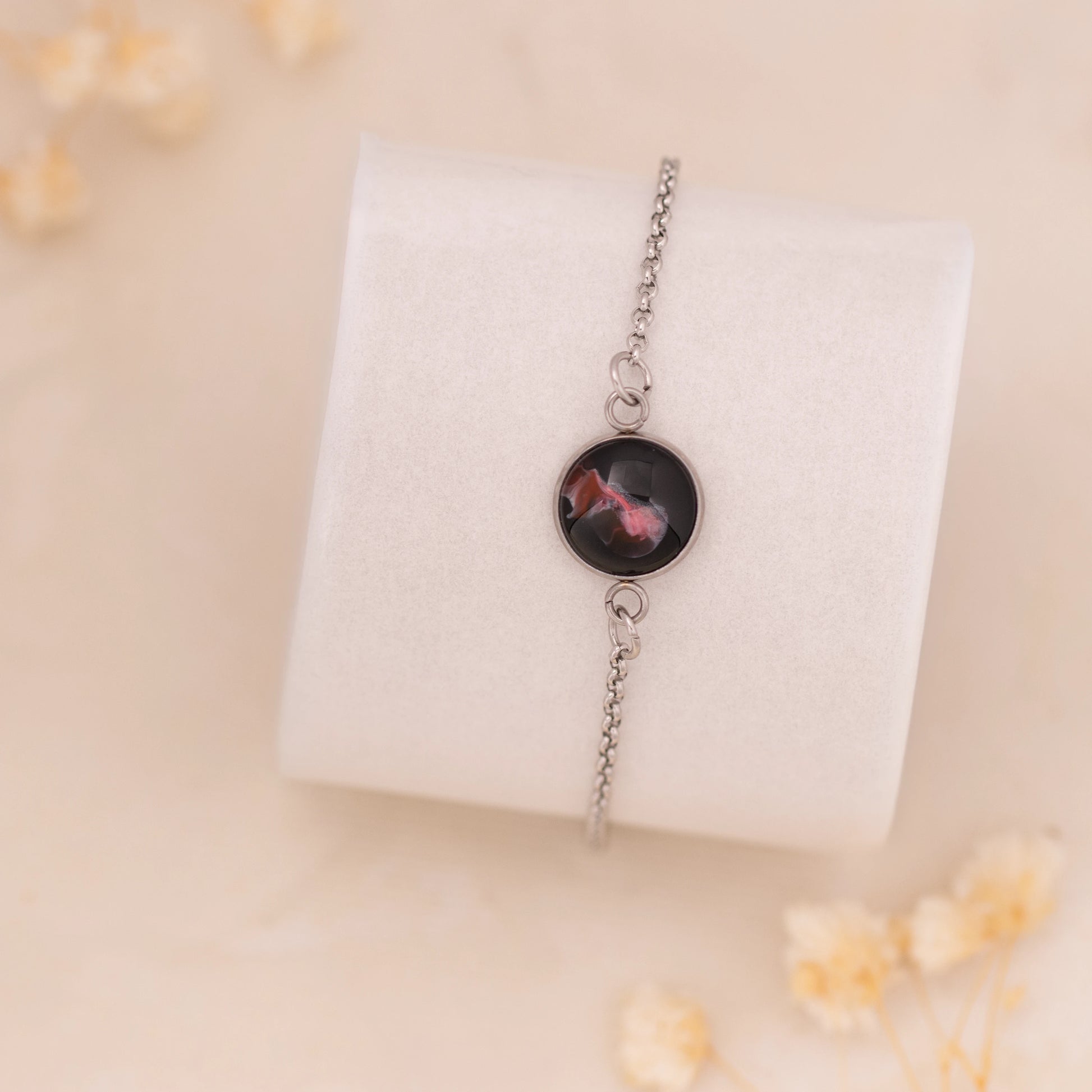 Dar Suad bracelet featuring abstract artwork in black, red, and silver with a stainless steel setting.