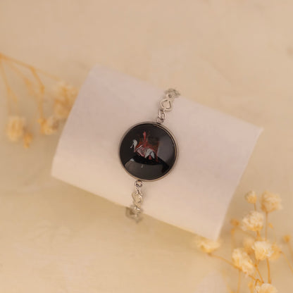 Dar Suad bracelet featuring one-of-a-kind original artwork in black, red, and silver with a stainless steel setting.