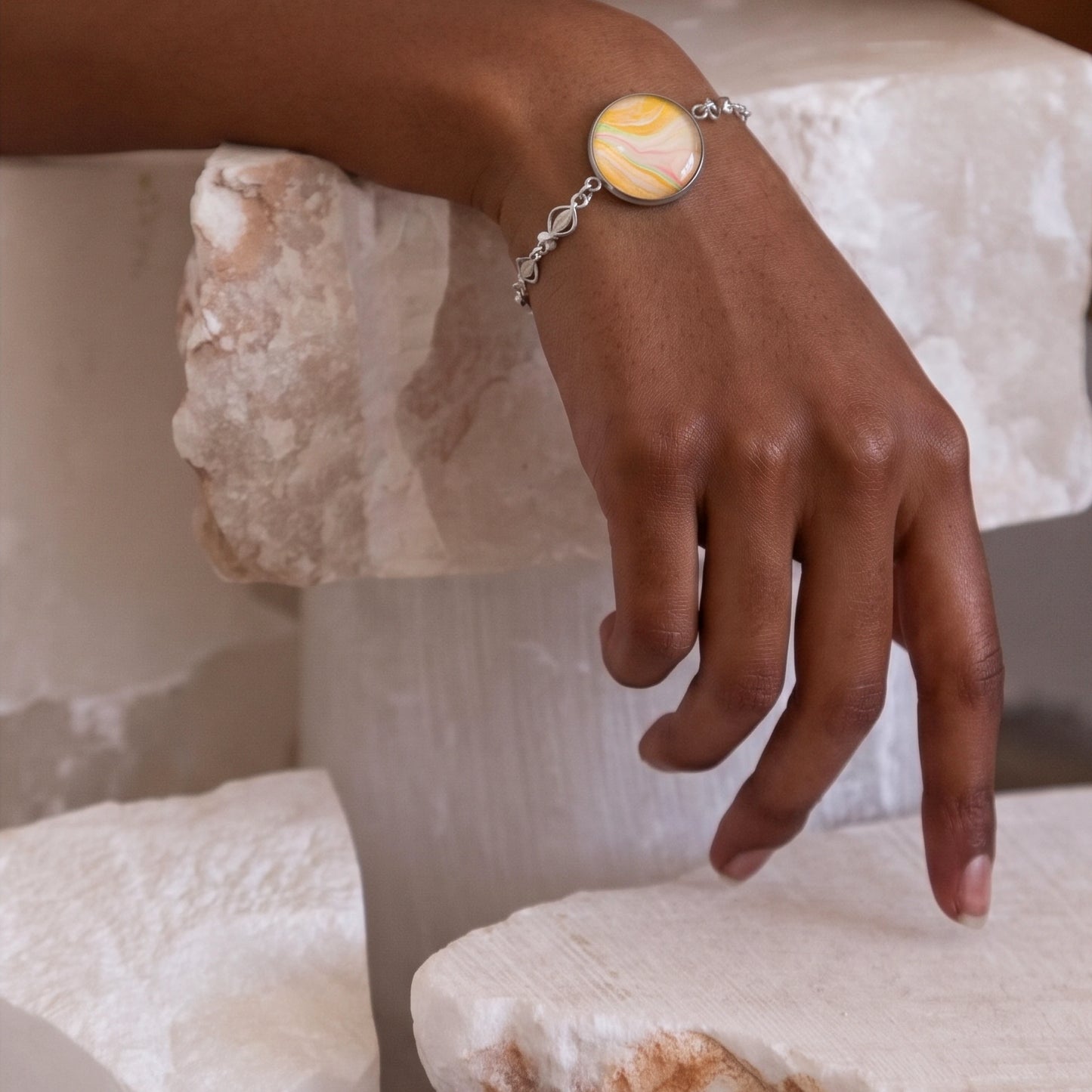 Model wearing Dar Suad stainless steel bracelet featuring one-of-a-kind original artwork in yellow, white, and pink.