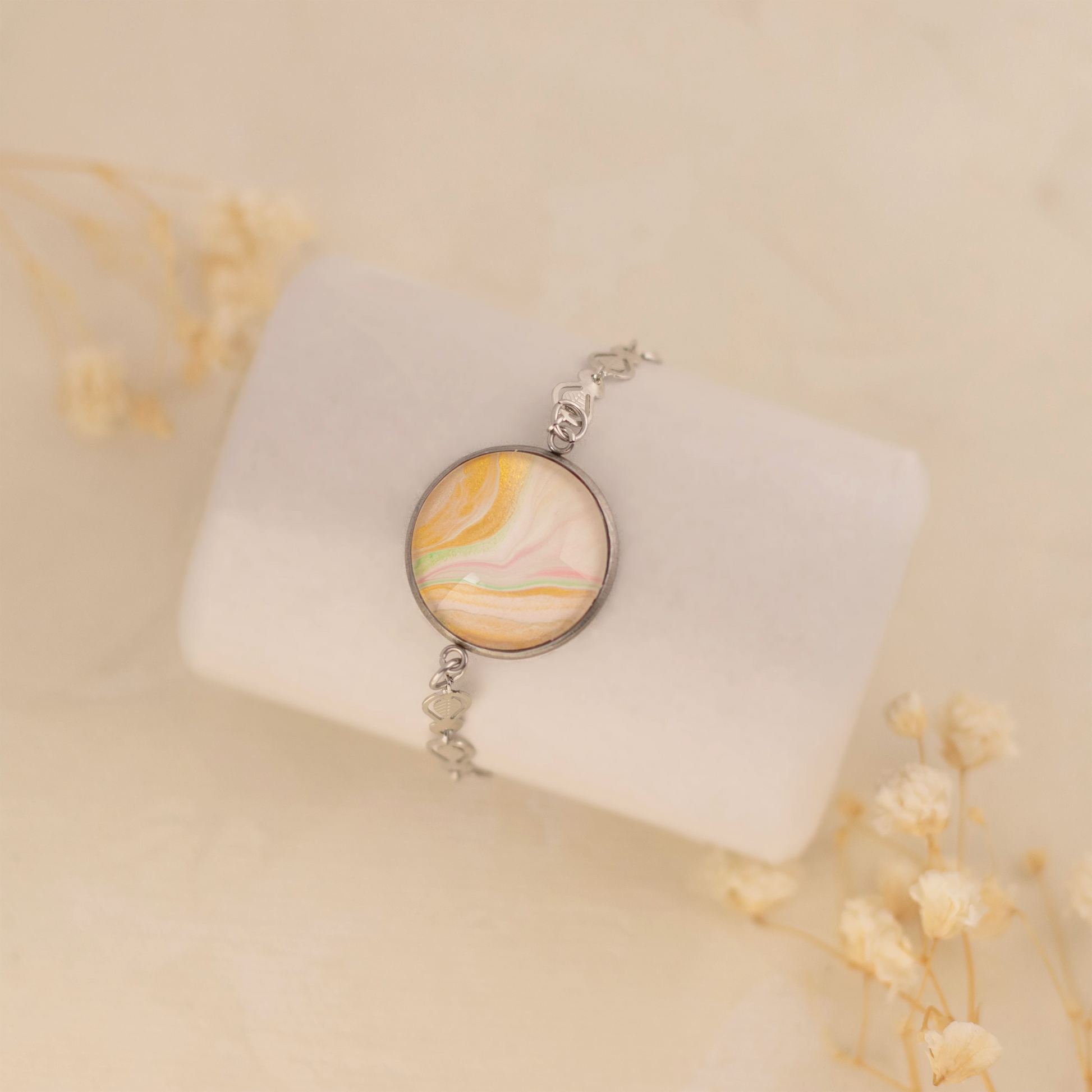 Dar Suad bracelet featuring one-of-a-kind original artwork in yellow, white, and pink with a stainless steel setting.