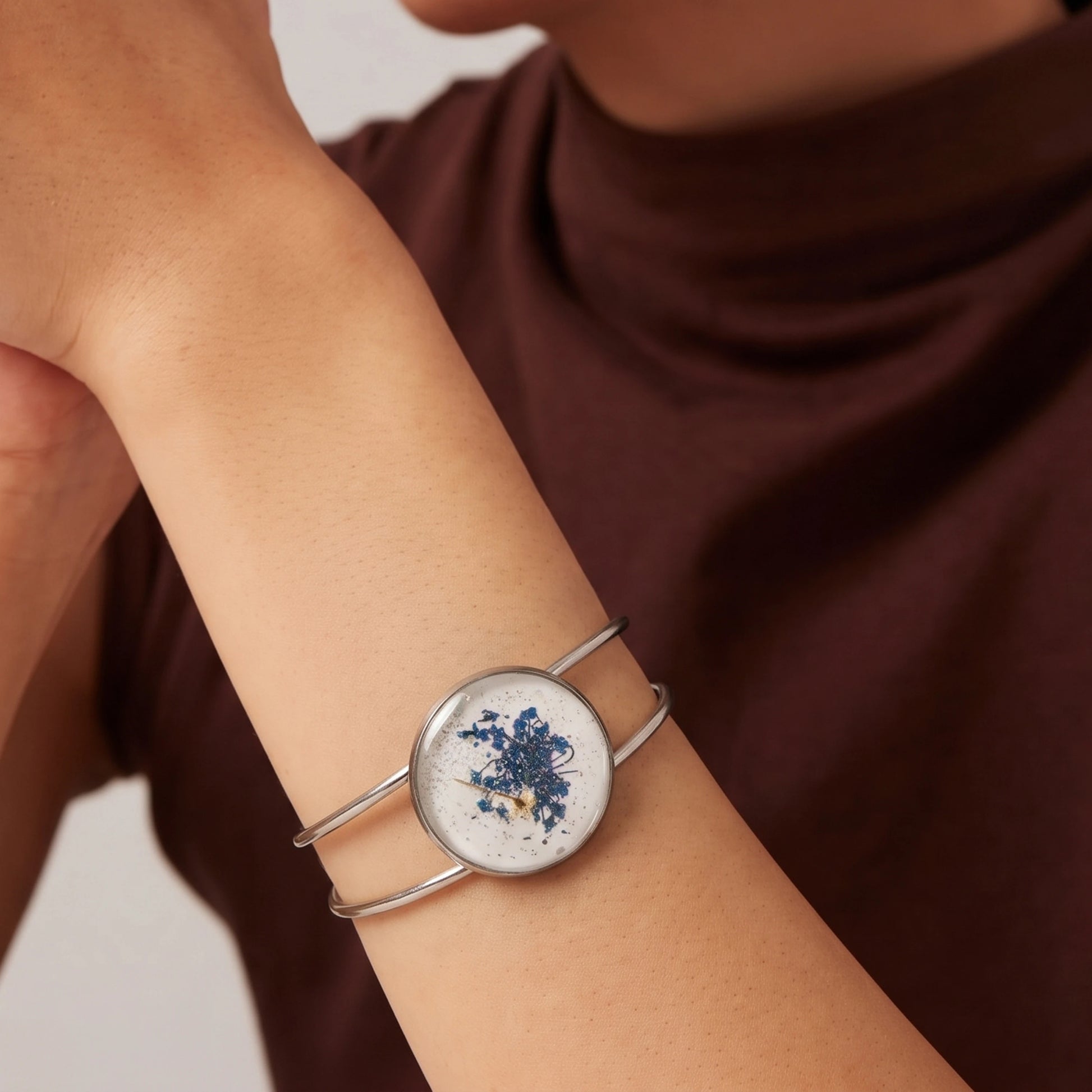 Model wearing Dar Suad alloy bracelet featuring one-of-a-kind original artwork in white and blue.