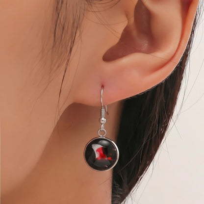 Model wearing Dar Suad stainless steel earring featuring abstract artwork in black, red and silver.