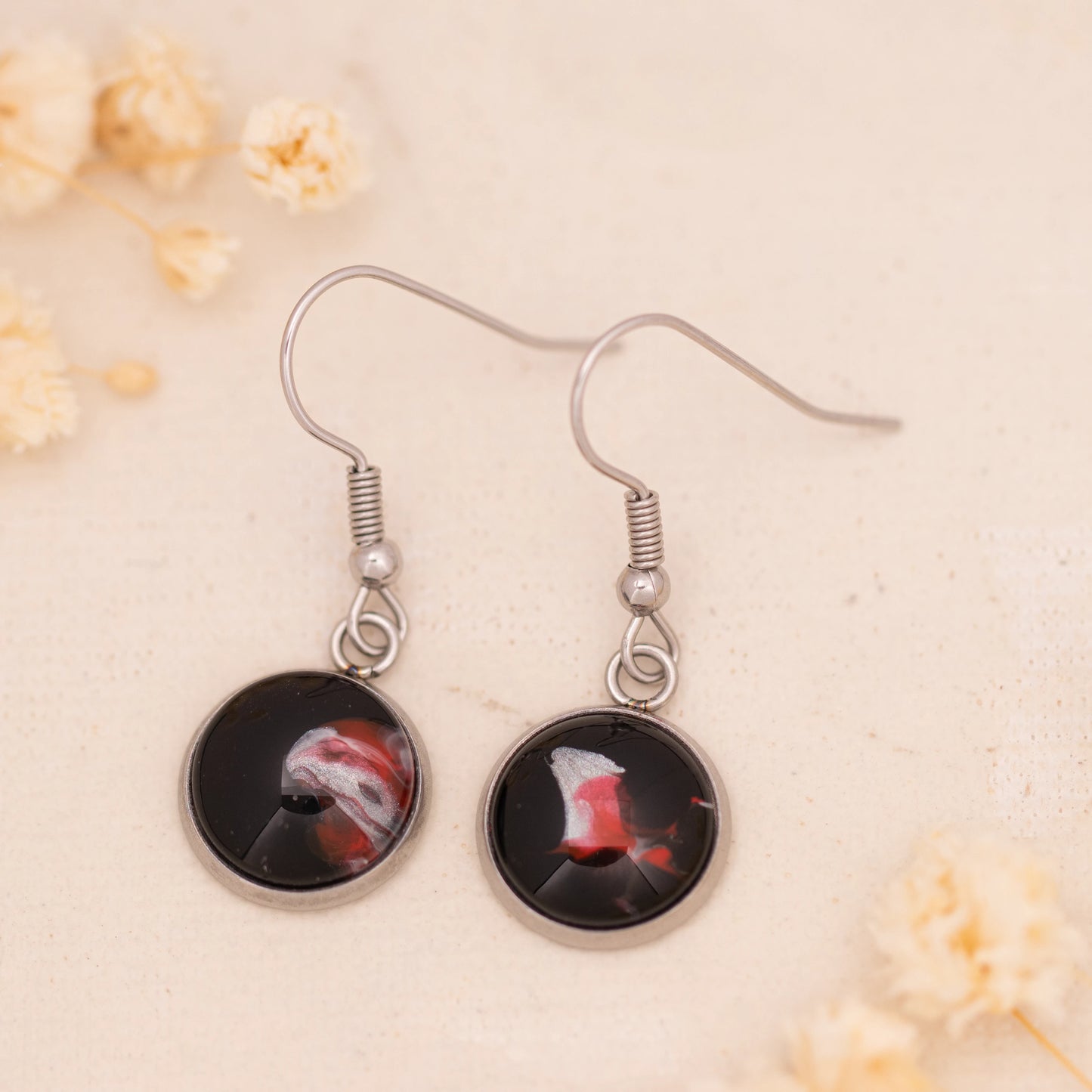 Dar Suad earrings featuring abstract artwork in black, red and silver with a stainless steel setting.