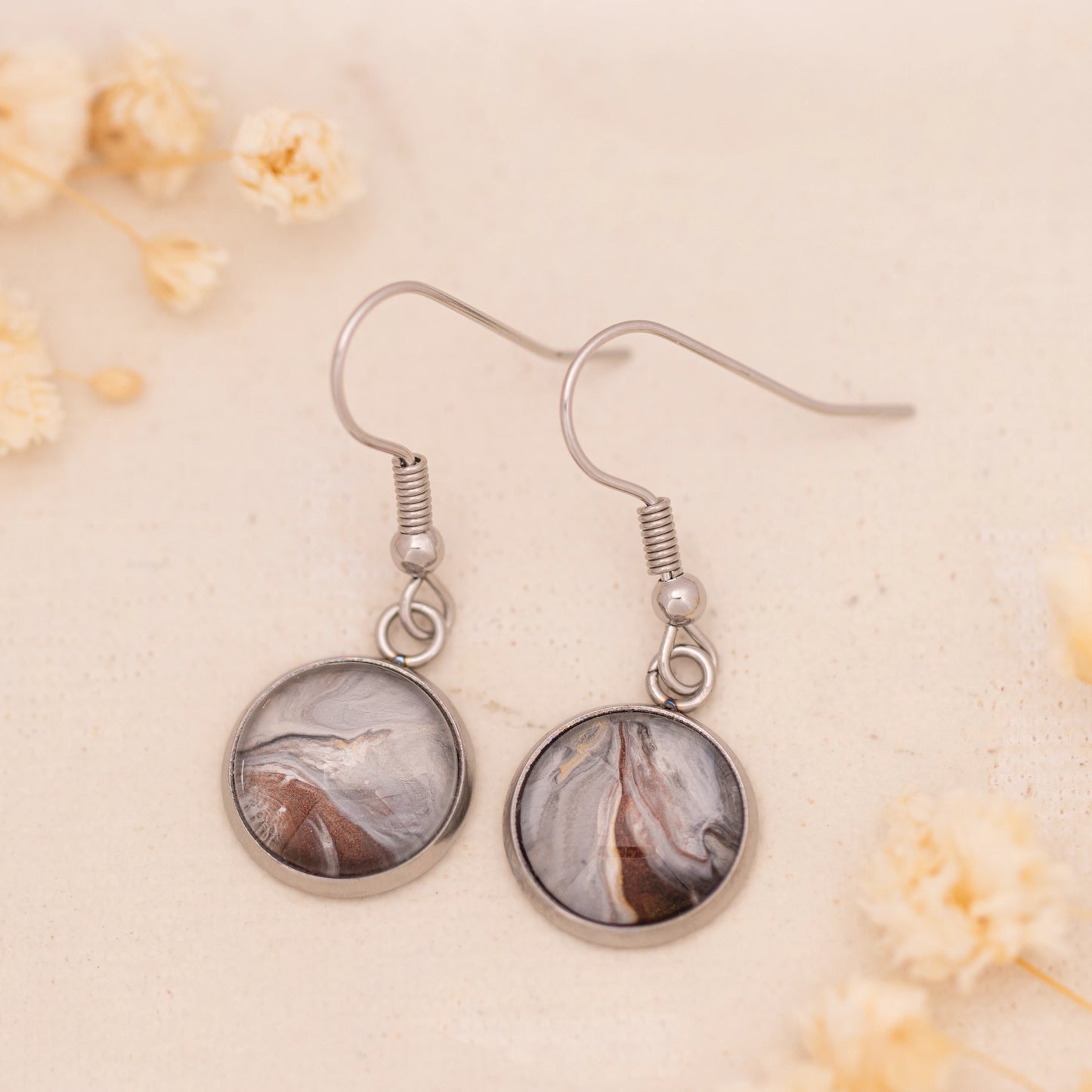 Dar Suad earrings featuring marbling artwork in grey, brown, and silver with a stainless steel setting.