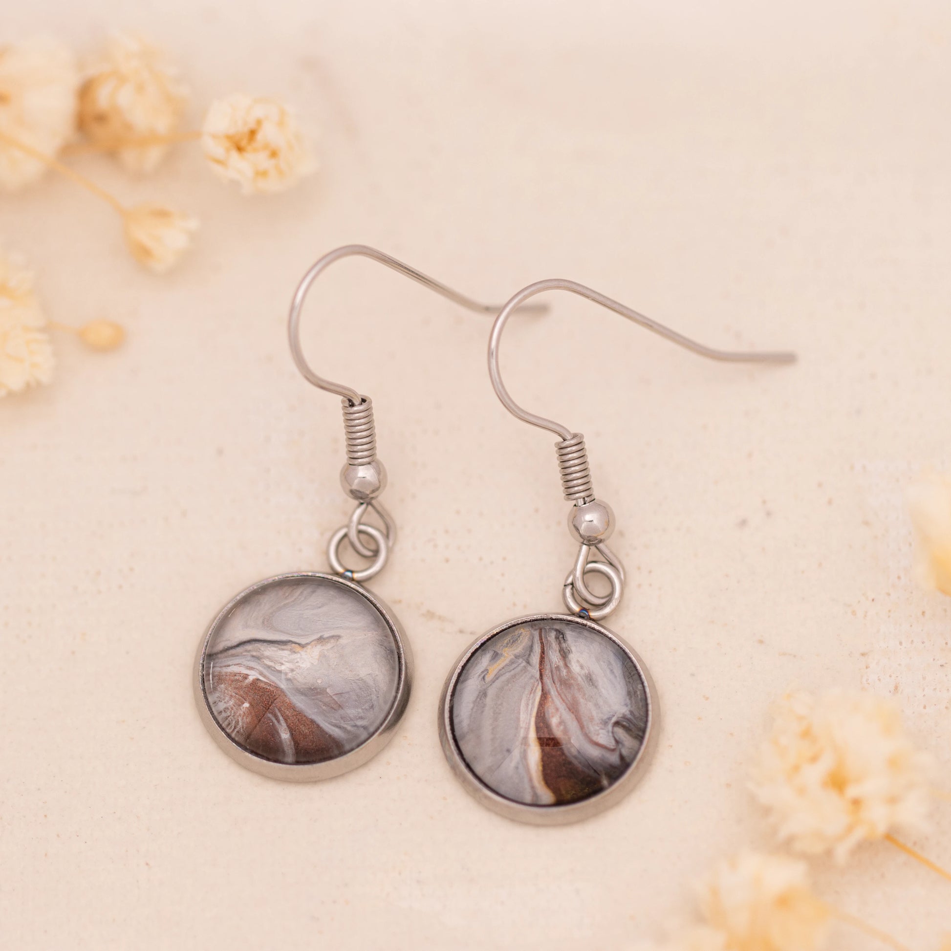 Dar Suad earrings featuring marbling artwork in grey, brown, and silver with a stainless steel setting.