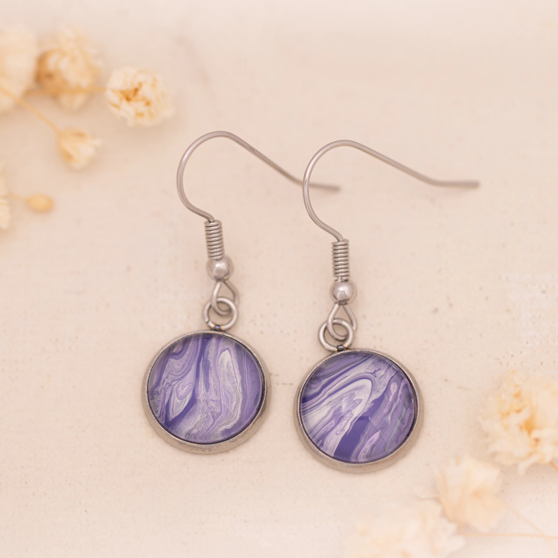 Dar Suad earrings featuring marbling artwork in purple and white with a stainless steel setting.