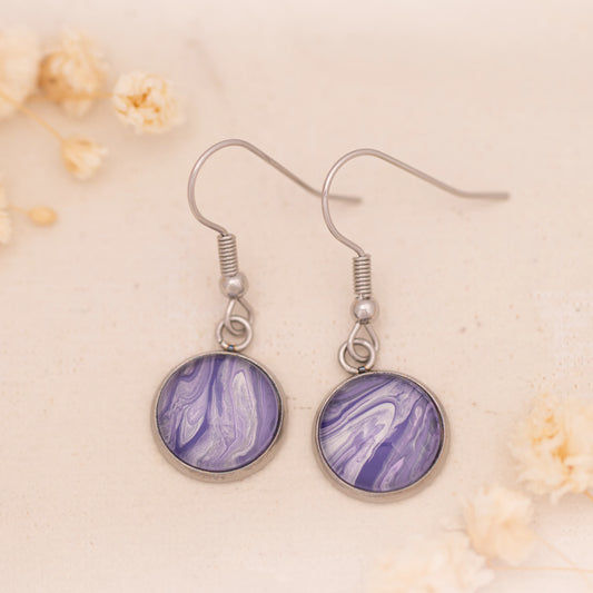 Dar Suad earrings featuring marbling artwork in purple and white with a stainless steel setting.