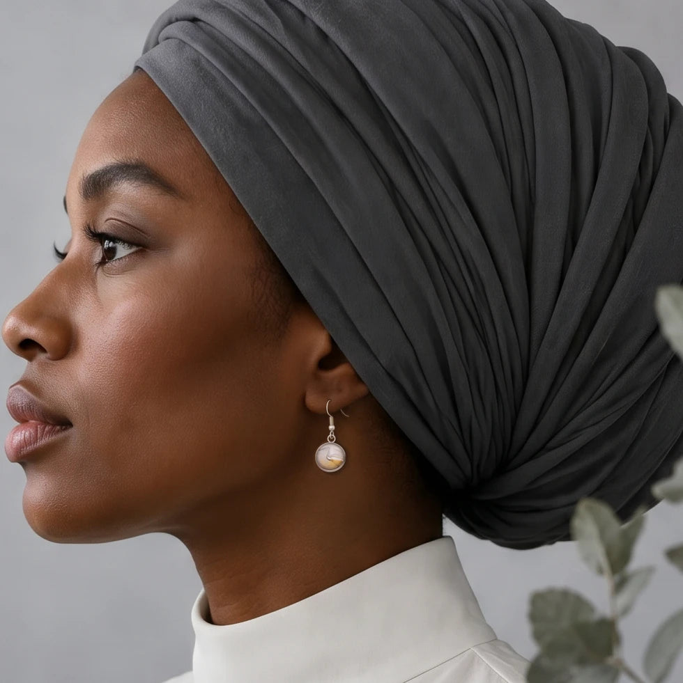 Model wearing Dar Suad stainless steel earrings featuring marbling artwork in white, grey, and bronze.