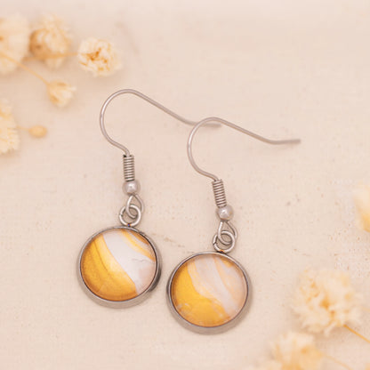 Dar Suad earrings featuring desert marbling artwork in yellow and white with a stainless steel setting.