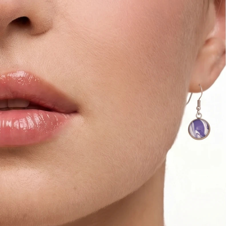Model wearing Dar Suad stainless steel earrings featuring marbling artwork in purple and white.