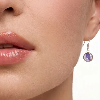 Model wearing Dar Suad stainless steel earrings featuring marbling artwork in purple and white.