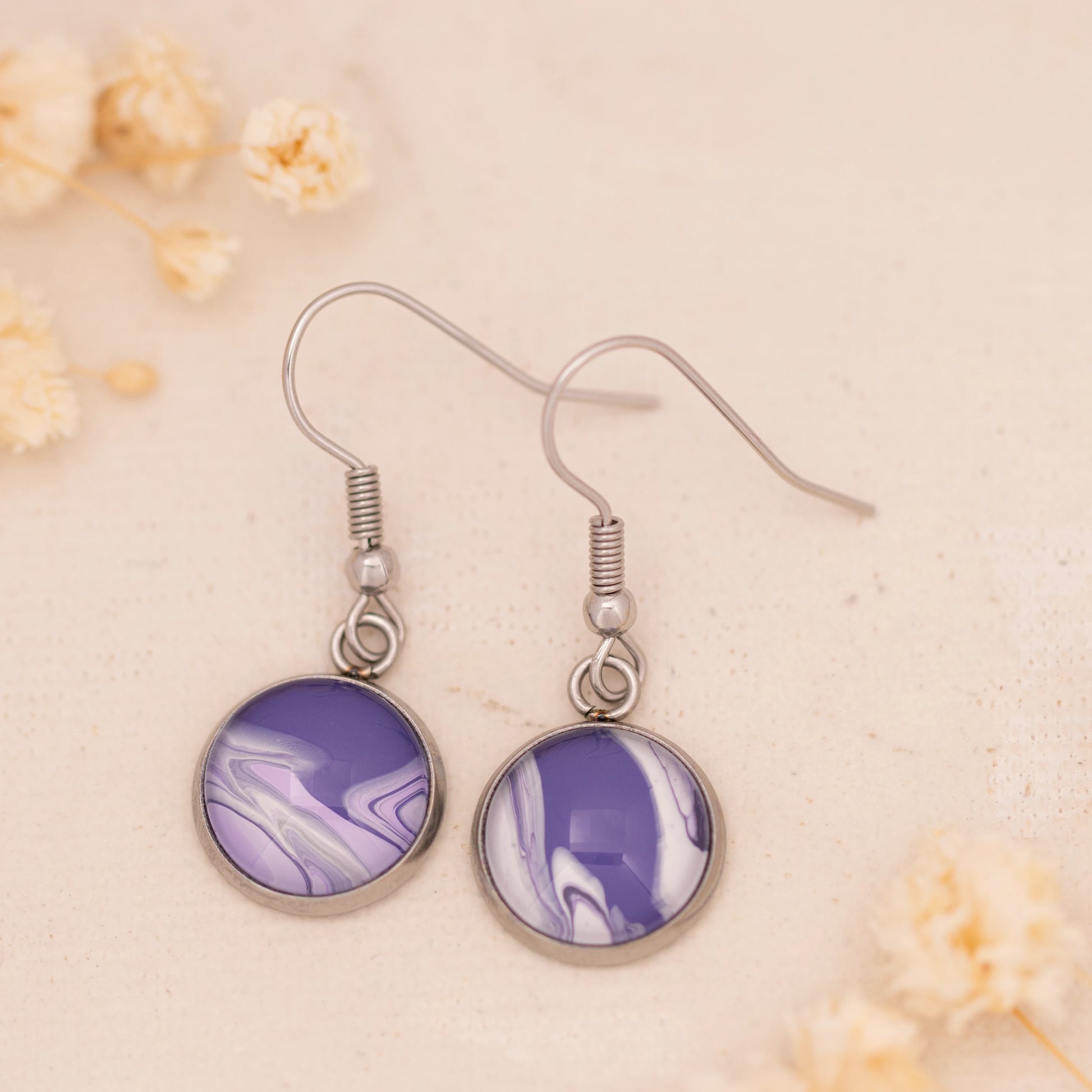 Dar Suad earrings featuring marbling artwork in purple and white with a stainless steel setting.