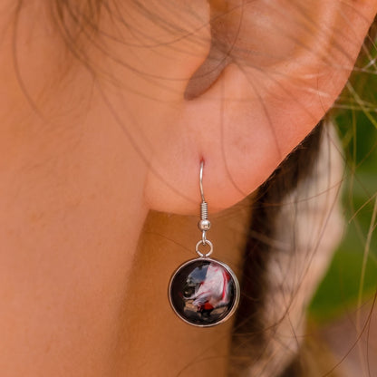 Model wearing Dar Suad stainless steel earrings featuring abstract artwork in black, red, and silver.