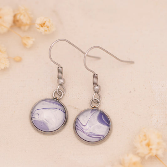 Dar Suad earrings featuring marbling artwork in purple and white with a stainless steel setting.