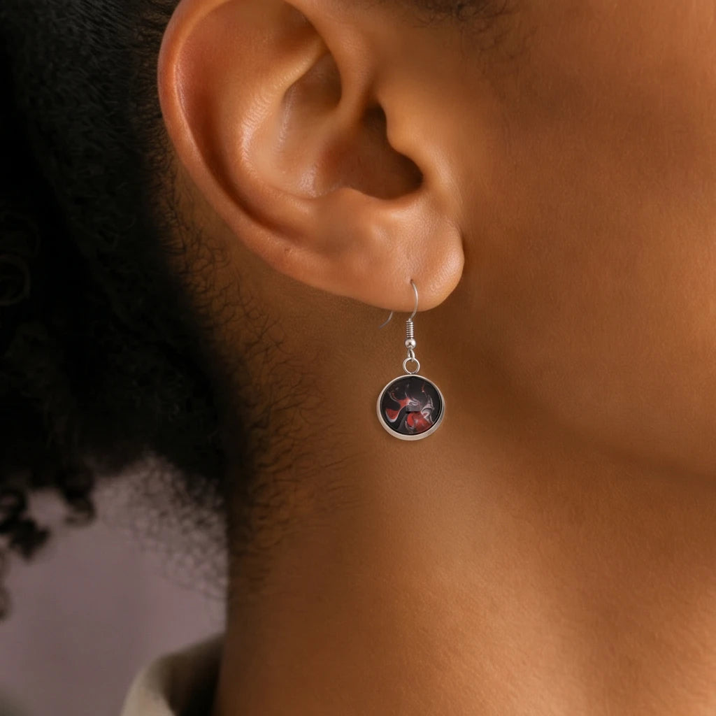 Model wearing Dar Suad stainless steel earrings featuring abstract artwork in black, red, and silver.