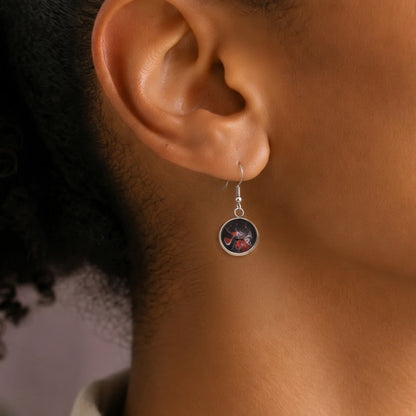 Model wearing Dar Suad stainless steel earrings featuring abstract artwork in black, red, and silver.
