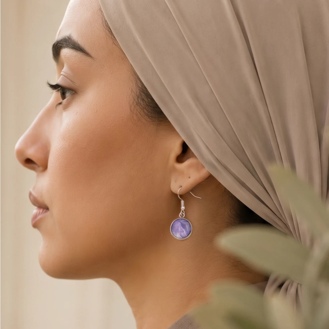 Model wearing Dar Suad stainless steel earrings featuring marbling artwork in purple and grey.