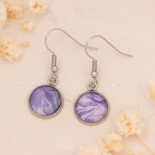 Dar Suad earrings featuring marbling artwork in purple and grey with a stainless steel setting.