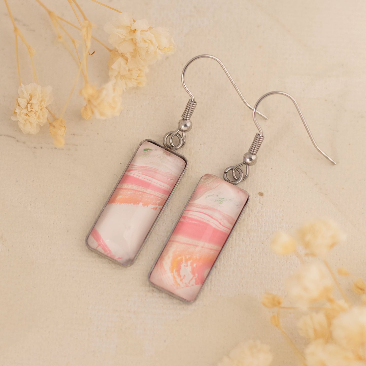 Dar Suad earrings featuring one-of-a-kind original artwork in pink and white with a stainless steel setting.