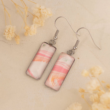 Dar Suad earrings featuring one-of-a-kind original artwork in pink and white with a stainless steel setting.