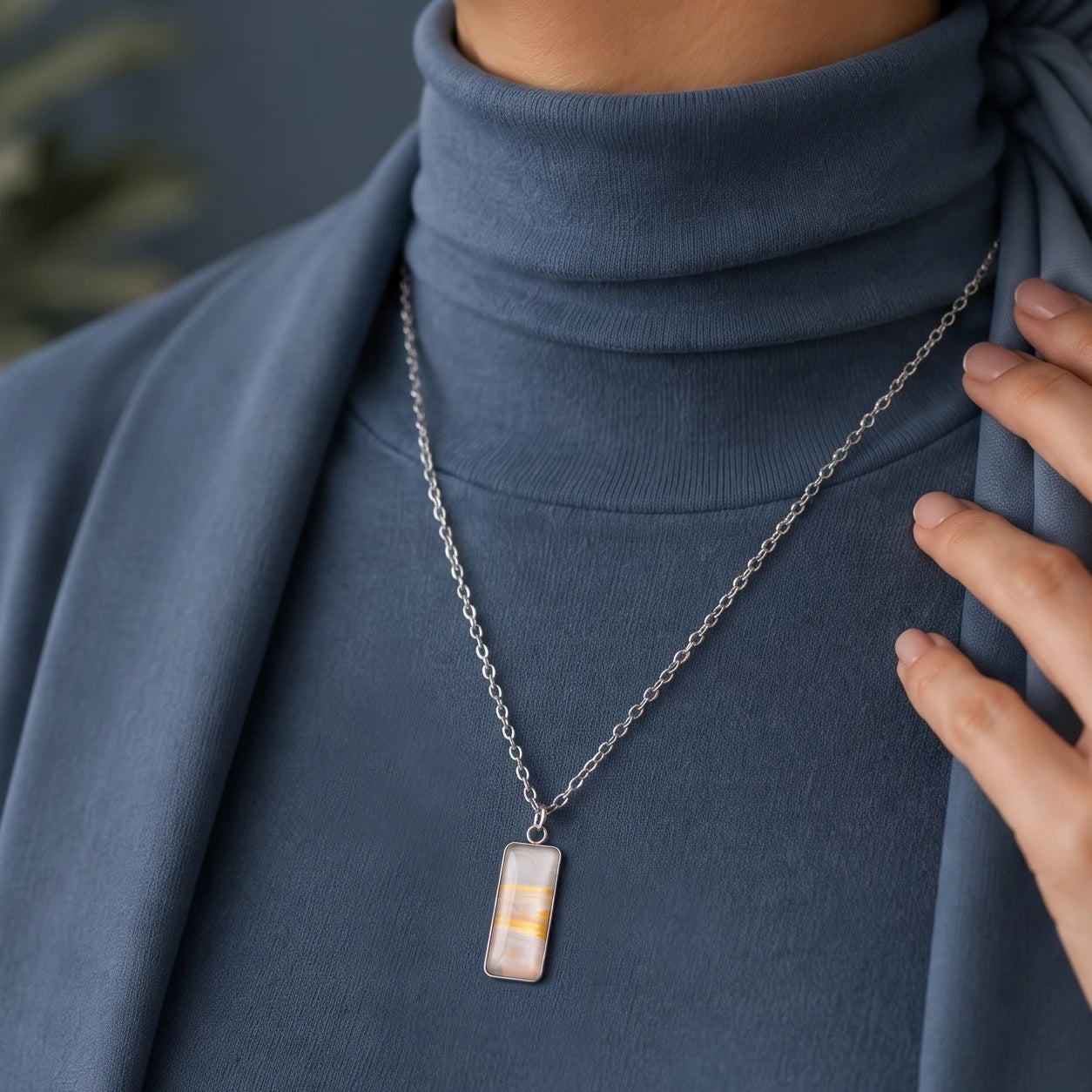 Model wearing Dar Suad stainless steel necklace featuring marbling artwork in white, yellow and grey.