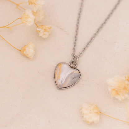 Dar Suad necklace featuring marbling artwork in white, yellow and grey with a stainless steel setting.