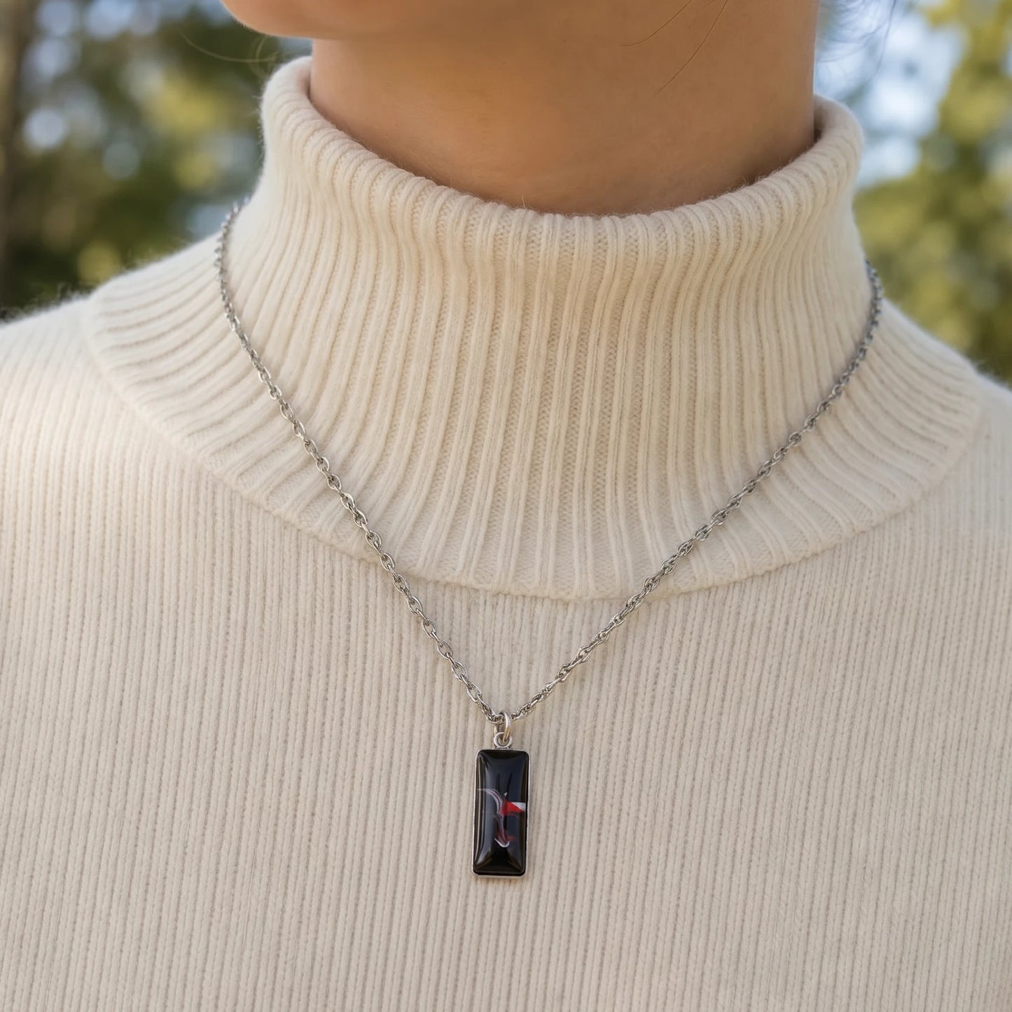 Model wearing Dar Suad stainless steel necklace featuring abstract artwork in black, red and silver.