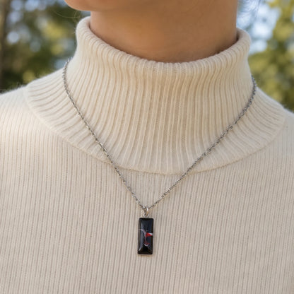 Model wearing Dar Suad stainless steel necklace featuring abstract artwork in black, red and silver.