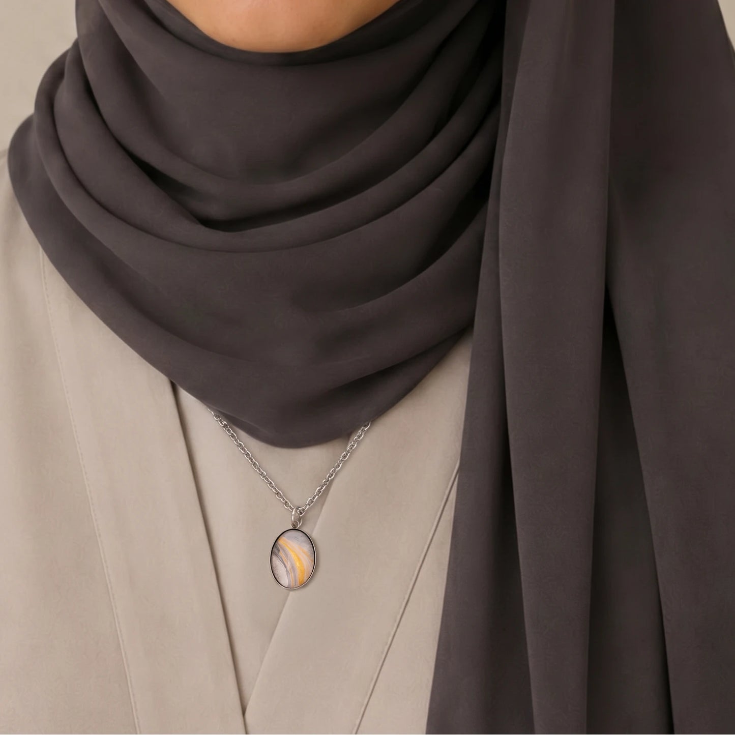 Model wearing Dar Suad stainless steel necklace featuring marbling artwork in white, yellow, and grey.