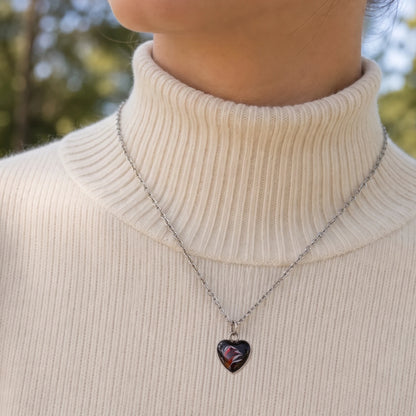 Model wearing Dar Suad stainless steel necklace featuring abstract artwork in black, silver, and red.