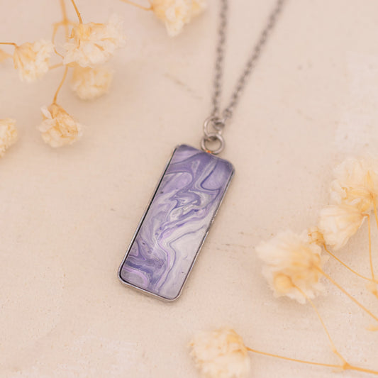 Dar Suad necklace featuring marbling artwork in purple and white with a stainless steel setting.